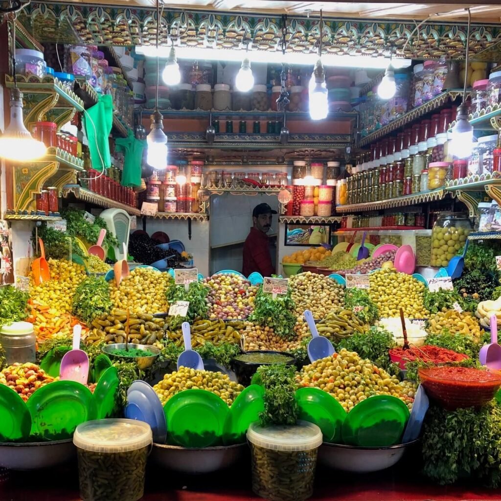 Vibrant Marrakech market stall featuring a wide variety of olives and pickles, with bright lighting and colorful containers, creating an inviting and lively shopping experience.
